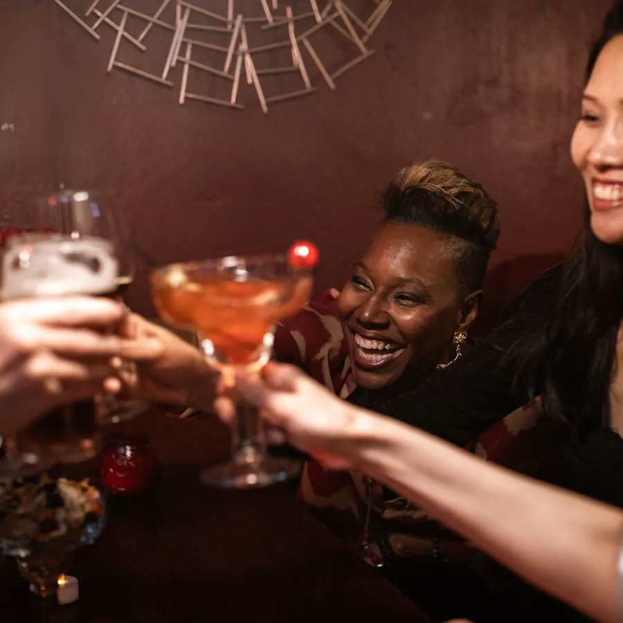 Friends toasting with cocktails at a bar